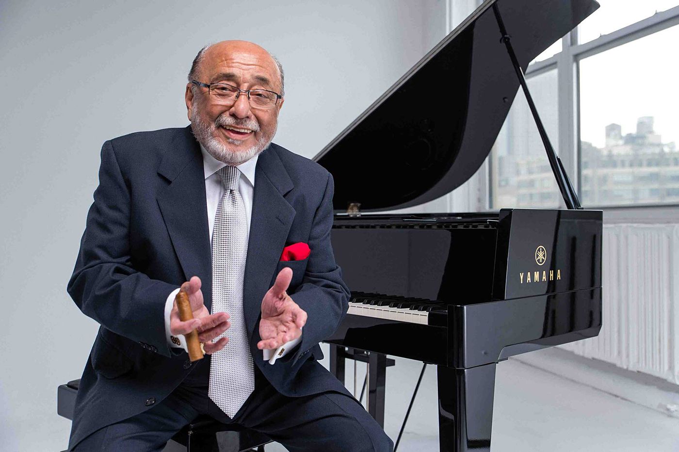 Eddie Palmieri, cerca de un piano y con un espléndido habano en su mano derecha.